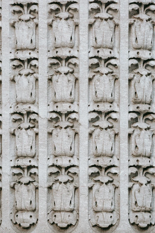 a close up of carvings on the side of a building, inspired by Taddeo Gaddi, unsplash, romanesque, seamless pattern :: symmetry, crumbling ancient skyscrapers, repeating pattern. seamless, made of concrete