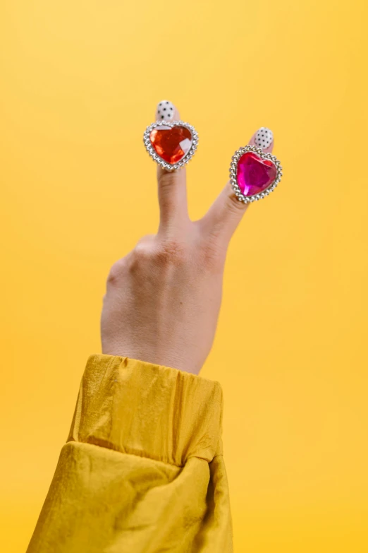 a woman's hand holding up two heart shaped rings, inspired by L. A. Ring, trending on pexels, pop art, bedazzled fruit costumes, adafruit, demur, made of crystal