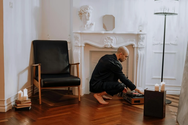 a man sitting on the floor working on a laptop, an album cover, by Emma Andijewska, pexels contest winner, video art, the living room, vin diesel with a tummy, dj set, sitting in french apartment