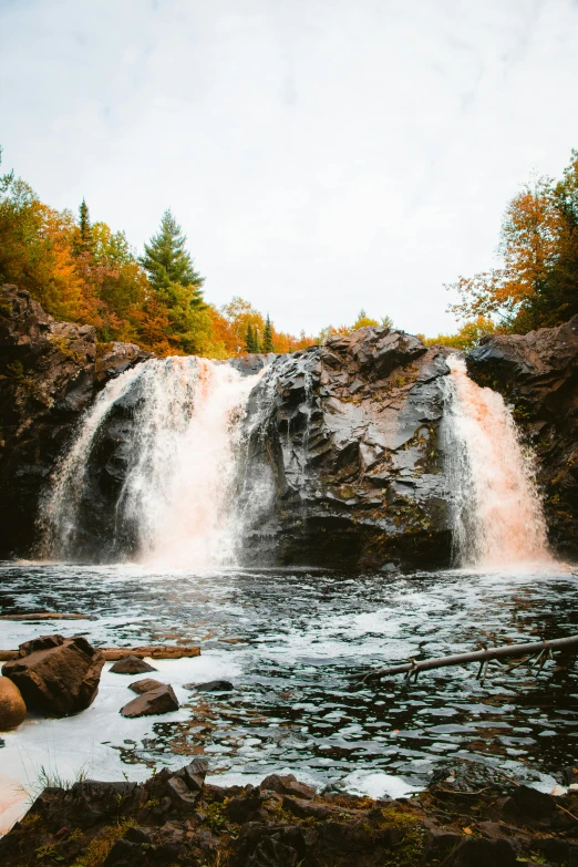 a large waterfall in the middle of a forest, in fall, boreal forest, lava waterfalls, fishing