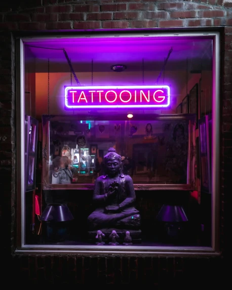 a buddha statue sits in the window of a tattoo shop, a tattoo, trending on unsplash, purple lighted street, lgbtq, sitting at a bar, tribal piercing and tatoos