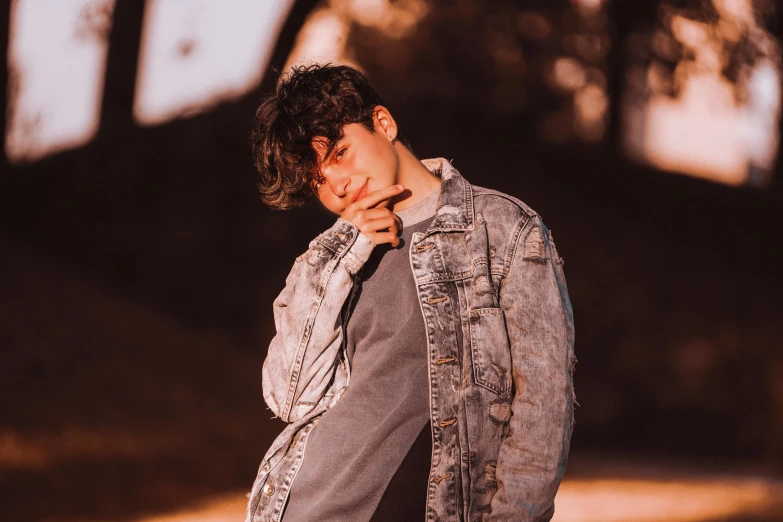 a man in a denim jacket posing for a picture, an album cover, trending on pexels, beautiful androgynous prince, soft morning lighting, bella poarch, ash thorp khyzyl saleem