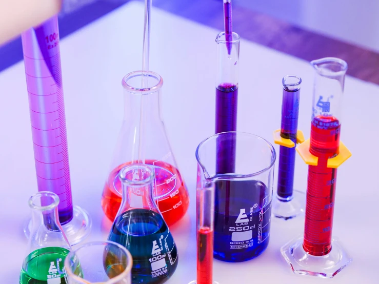 a group of test tubes sitting on top of a table, purple, colorful medical equipment, colorful aesthetic, high school