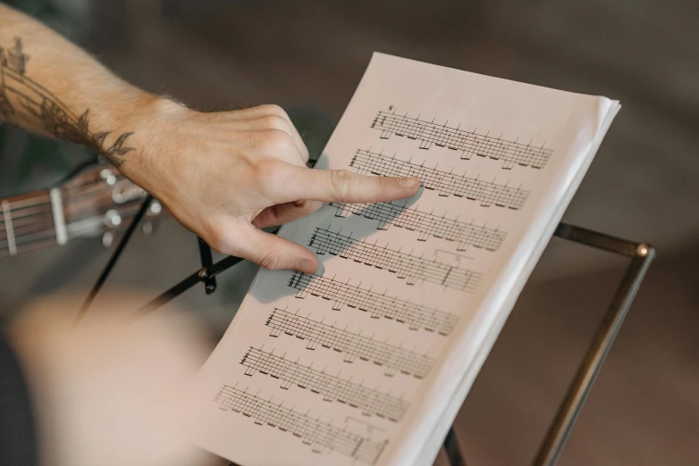 a close up of a person holding a sheet of music, multiple stories, bassist, on vellum, scales