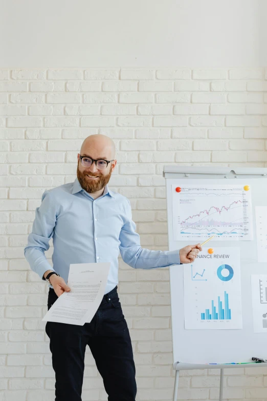 a man standing in front of a whiteboard holding papers, pexels contest winner, red beard, graphs, bald, vp of marketing