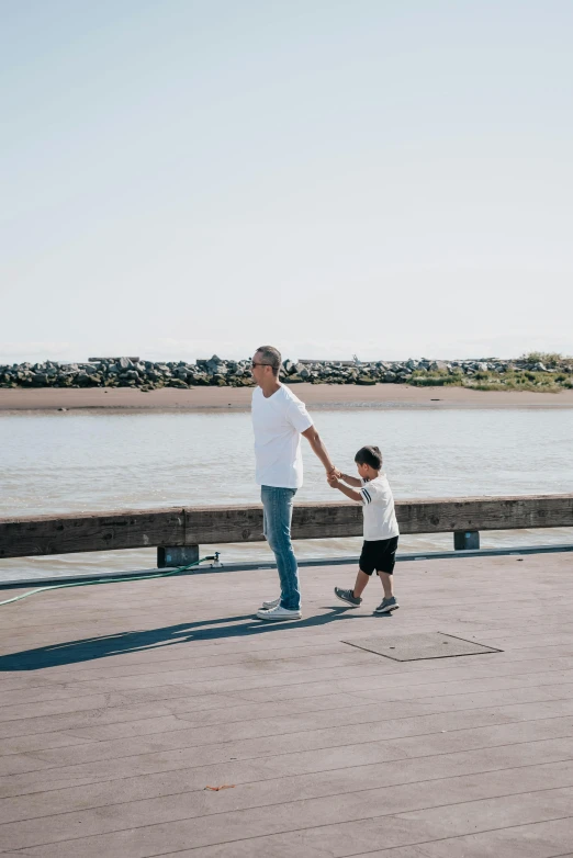 a man holding the hand of a little boy who is flying a kite, unsplash, happening, boardwalk, full body image, bay area, gray men