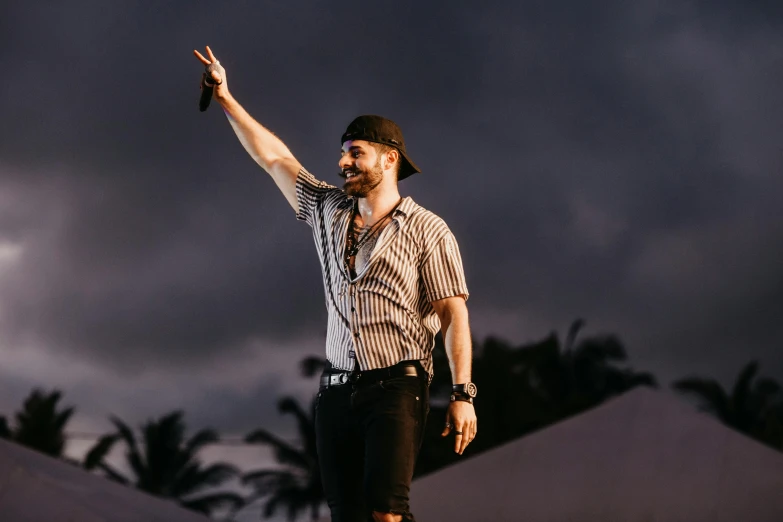 a man standing on top of a skateboard on top of a ramp, an album cover, by Robbie Trevino, pexels, renaissance, singer maluma, live performance, rum, he is wearing a hat