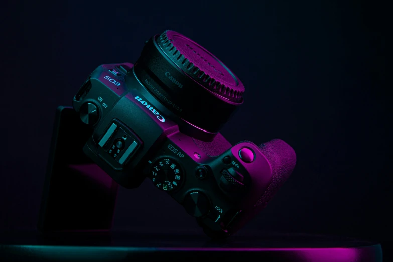 a close up of a camera on a table, by Adam Marczyński, unsplash contest winner, art photography, purple volumetric lighting, crown of (pink lasers), background canon, full body profile camera shot