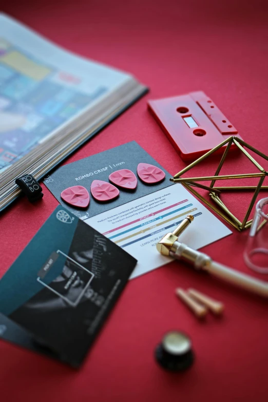 a close up of a bunch of items on a table, an album cover, red hot soldering iron, pair of keycards on table, glass and gold pipes, material design