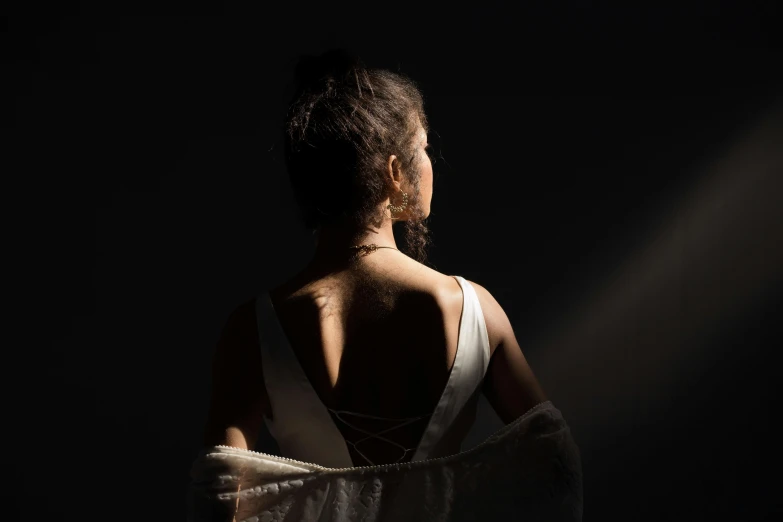 the back of a woman in a white dress, inspired by Théodule Ribot, pexels contest winner, light and space, dark. studio lighting, an asian woman, the sun at their back, dark-skinned