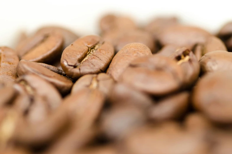 a pile of coffee beans sitting on top of a table, a macro photograph, by Thomas Häfner, unsplash, fan favorite, closeup 4k, colombian, thin dof