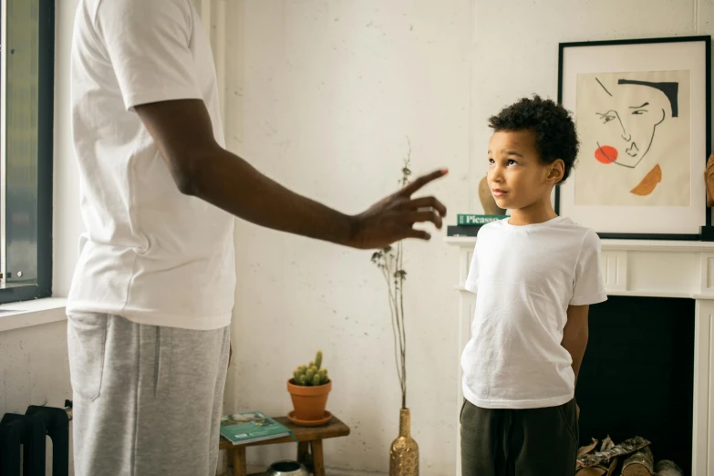 a man standing next to a young boy in a living room, pexels contest winner, reaching out to each other, scolding, wearing pants and a t-shirt, promotional image