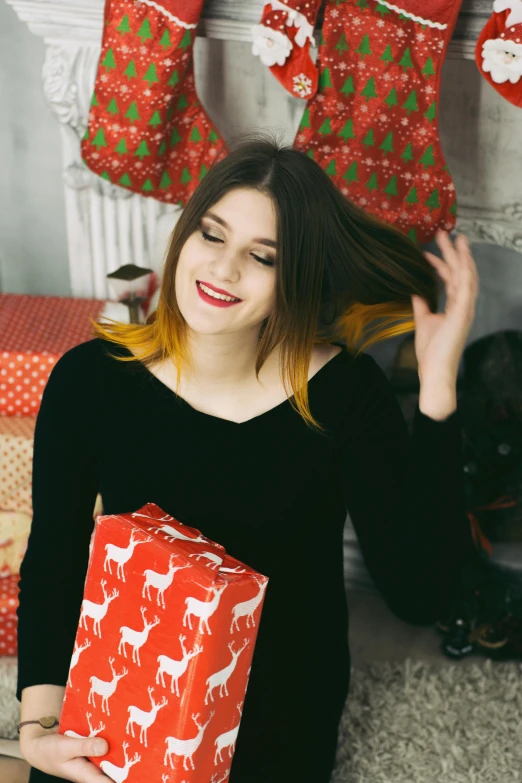 a woman sitting in front of a christmas tree holding a present, pexels contest winner, two tone hair dye, black and yellow and red scheme, anastasia ovchinnikova, square