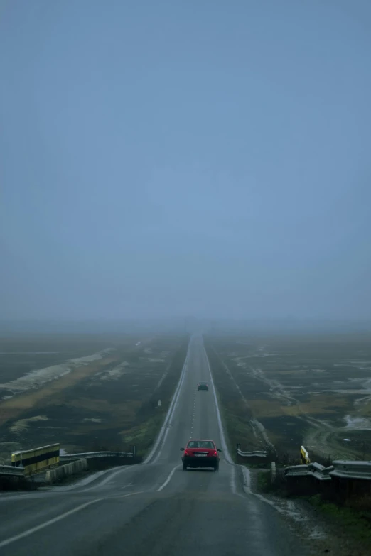 a car driving down a road on a foggy day, inspired by Zhang Kechun, postminimalism, sky - high view, runway, stålenhag, 1 8 mm wide shot