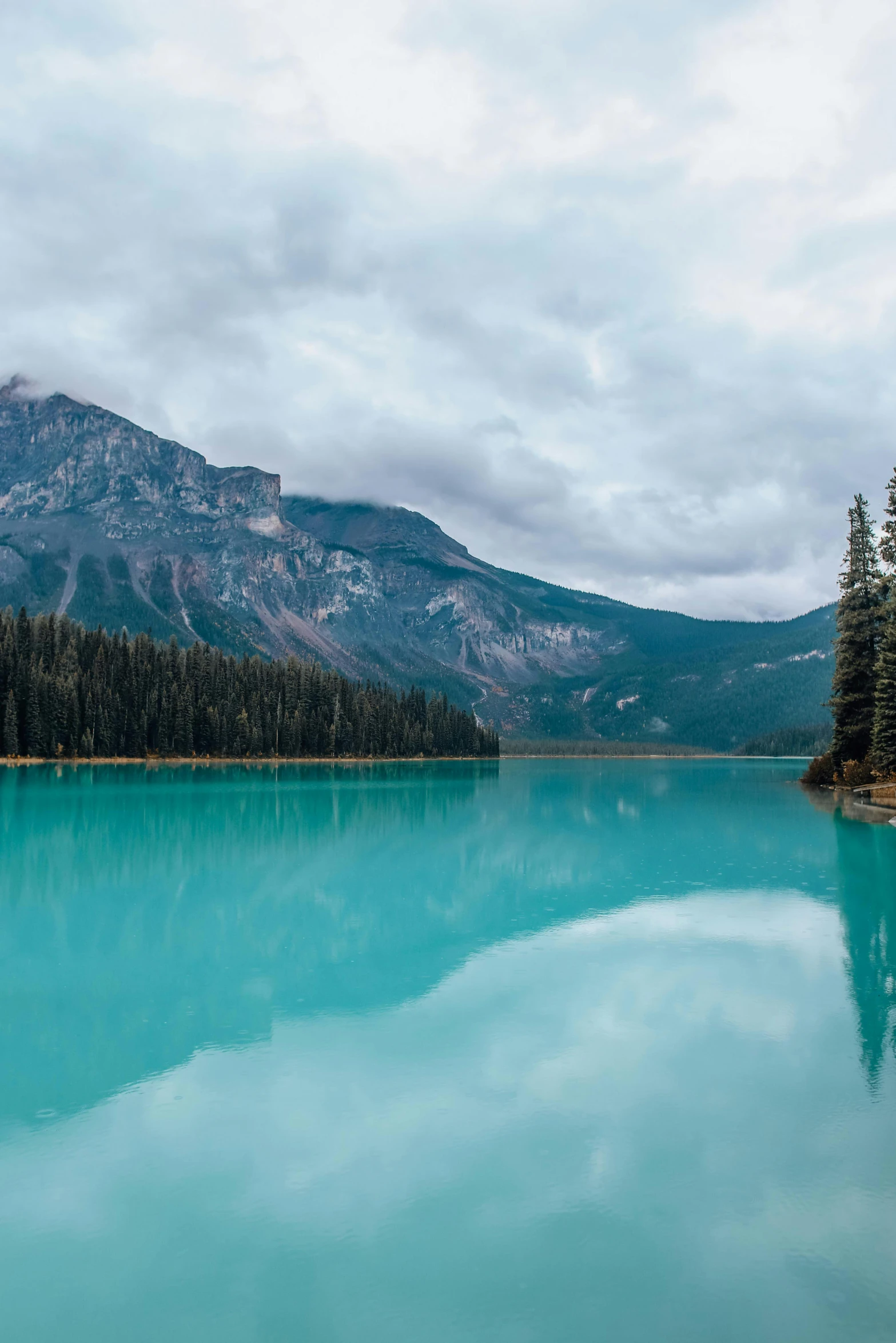 a body of water with a mountain in the background, banff national park, carribean turquoise water, vibrant but dreary, wet relections