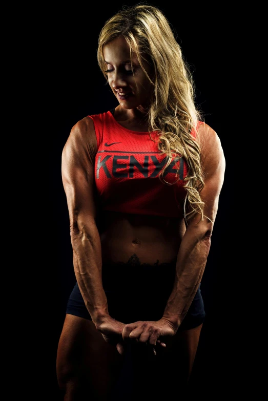 a woman posing for a picture in the dark, by Adam Manyoki, athletic crossfit build, red vest, unmistakably kenyan, promotional photo