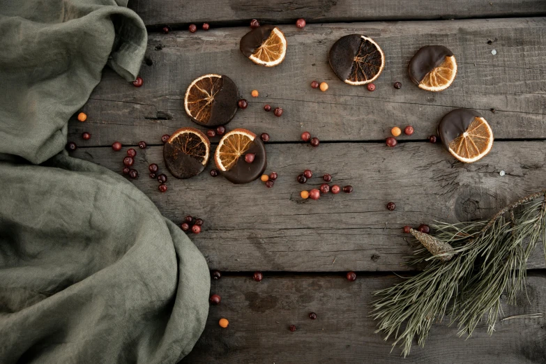 a bunch of orange slices sitting on top of a wooden table, chocolate, evergreen branches, dirty linen robes, thumbnail