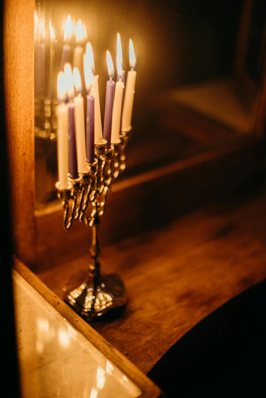 a group of lit candles sitting on top of a table, on a candle holder, bathed in golden light, iconic scene, purple dim light