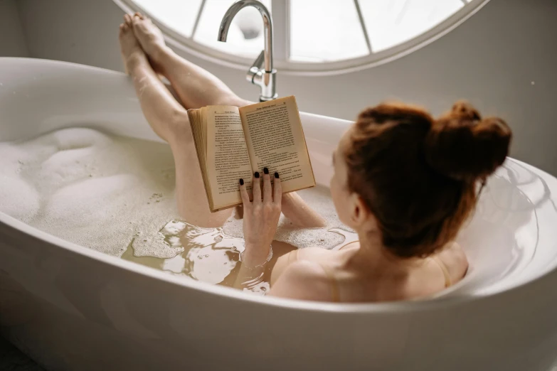 a woman reading a book in a bathtub, by Julia Pishtar, pexels contest winner, pale - skinned, bumpy skin, various posed, readhead