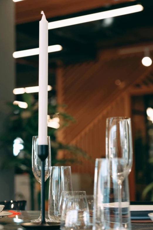 a candle sitting on top of a table next to wine glasses, table with microphones, crisp clean shapes, indoor setting, stems