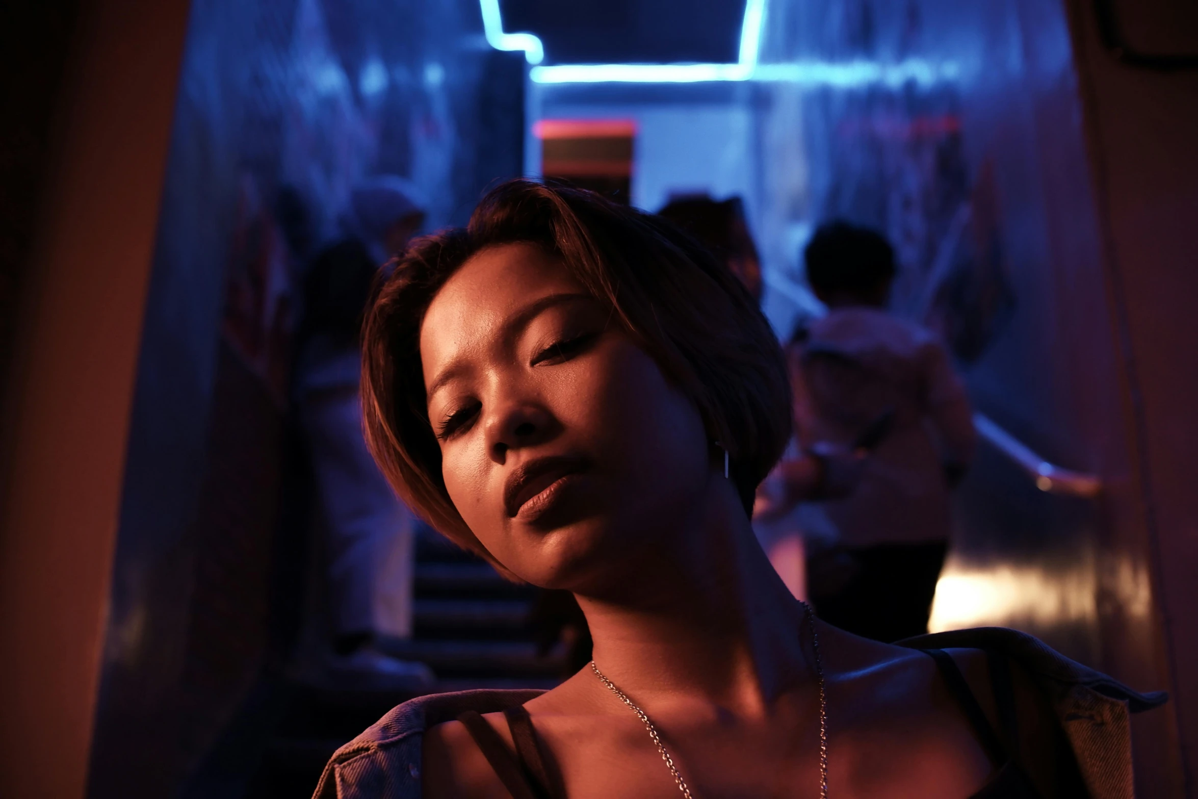 a woman standing in a hallway with her eyes closed, inspired by Liam Wong, pexels contest winner, neo-figurative, in a nightclub, blue light accents, young asian woman, instagram picture