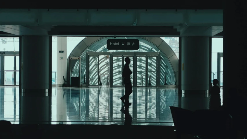 a couple of people that are standing in a building, inspired by Liam Wong, pexels contest winner, video art, black. airports, lonely human walking, cai xukun, in the early morning