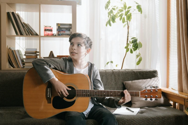 a boy sitting on a couch playing a guitar, pexels contest winner, greta thunberg, portrait sophie mudd, ad image, ::