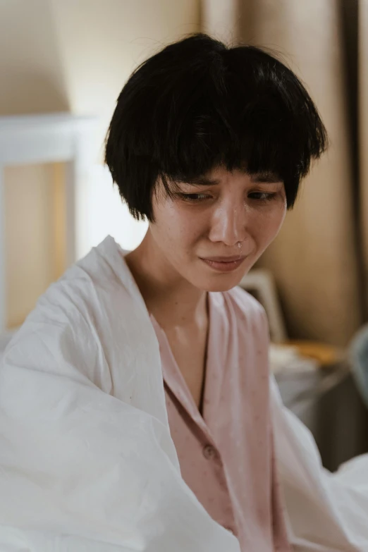 a woman sitting on a bed reading a book, by Ruth Jên, pexels contest winner, process art, jimin\'s right eyelid swollen, bathrobe, young adorable korean face, disappointed