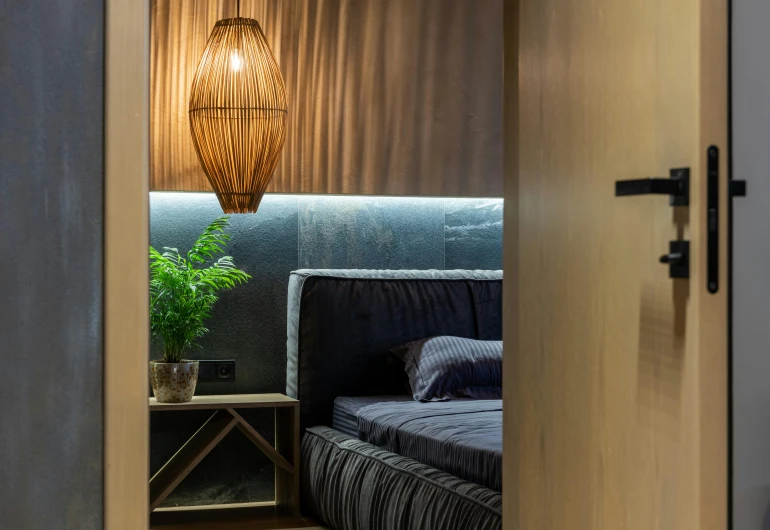 a bed sitting inside of a bedroom next to a lamp, by Adam Marczyński, light and space, bamboo, accent lighting, dark deco, inside a modern apartment