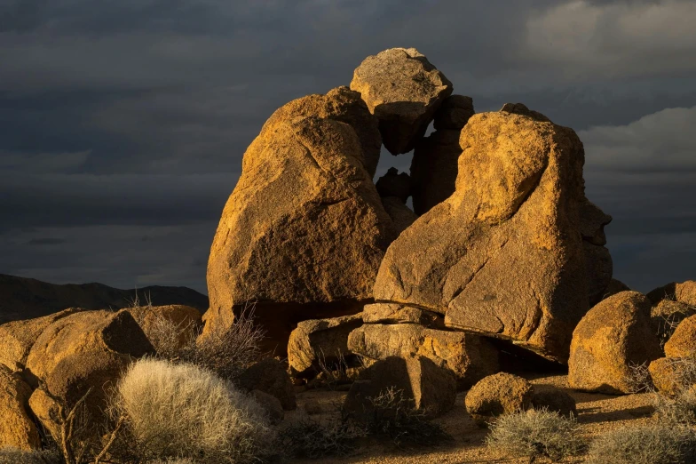 a couple of large rocks sitting on top of a dry grass covered field, by Peter Churcher, unsplash contest winner, australian tonalism, massive arch, evening light, tessellated planes of rock, mojave desert