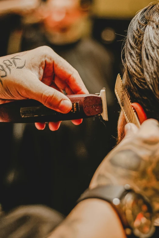 a man getting his hair cut at a barber shop, by Jesper Knudsen, trending on pexels, hand holding a knife, vintage vibe, neck zoomed in, tattooed