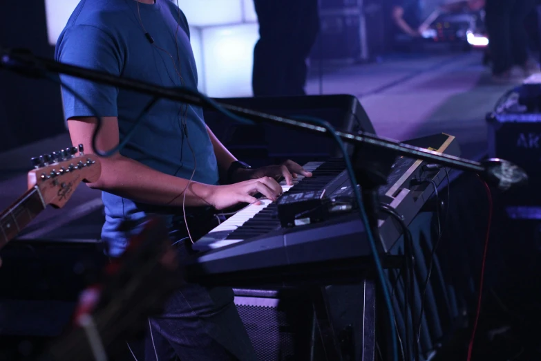 a man that is standing in front of a keyboard, band playing, colour corrected, close angle, worship
