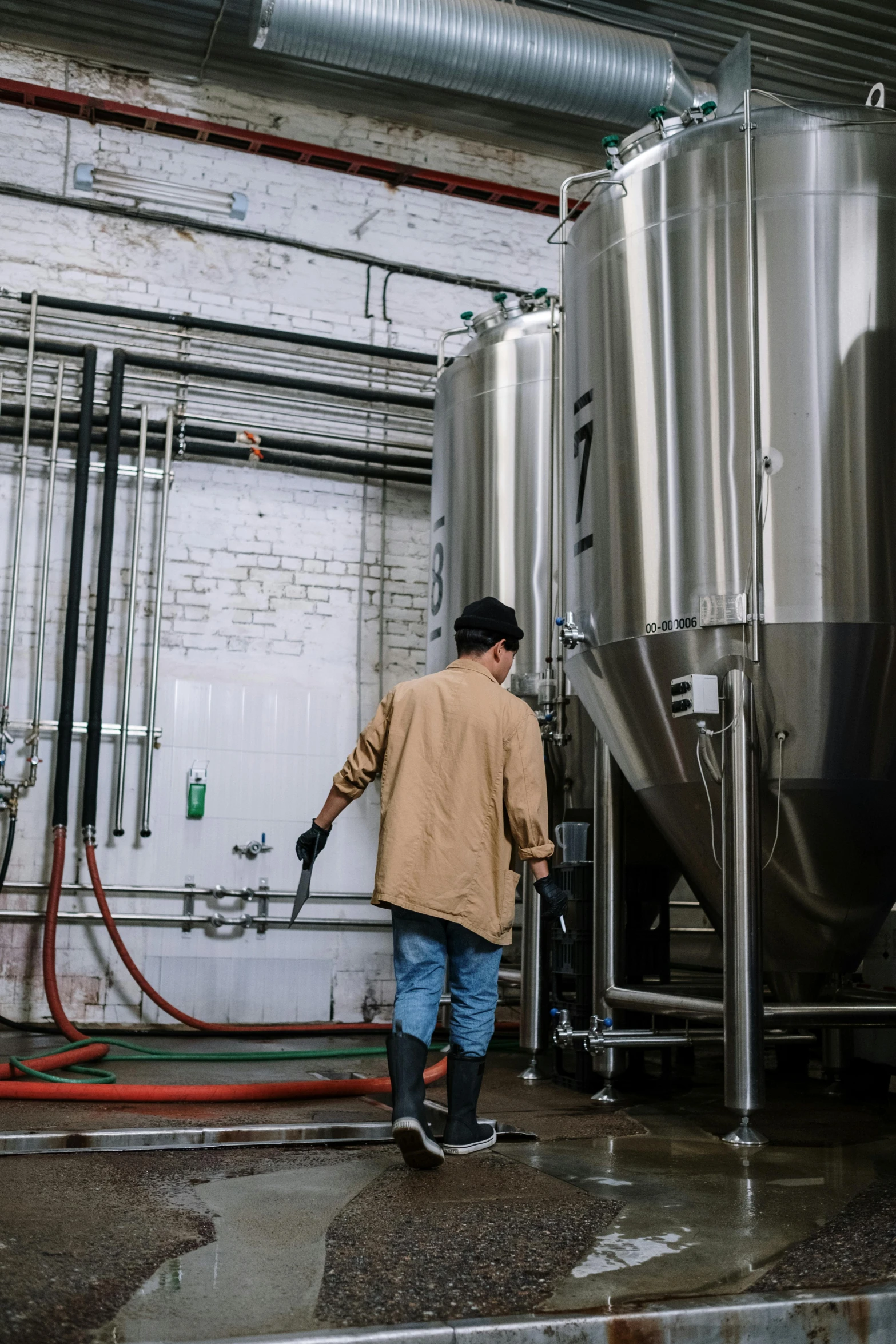 a man that is standing in front of some tanks, by Jason Felix, unsplash contest winner, process art, new england ipa, stainless steel, facing away, working