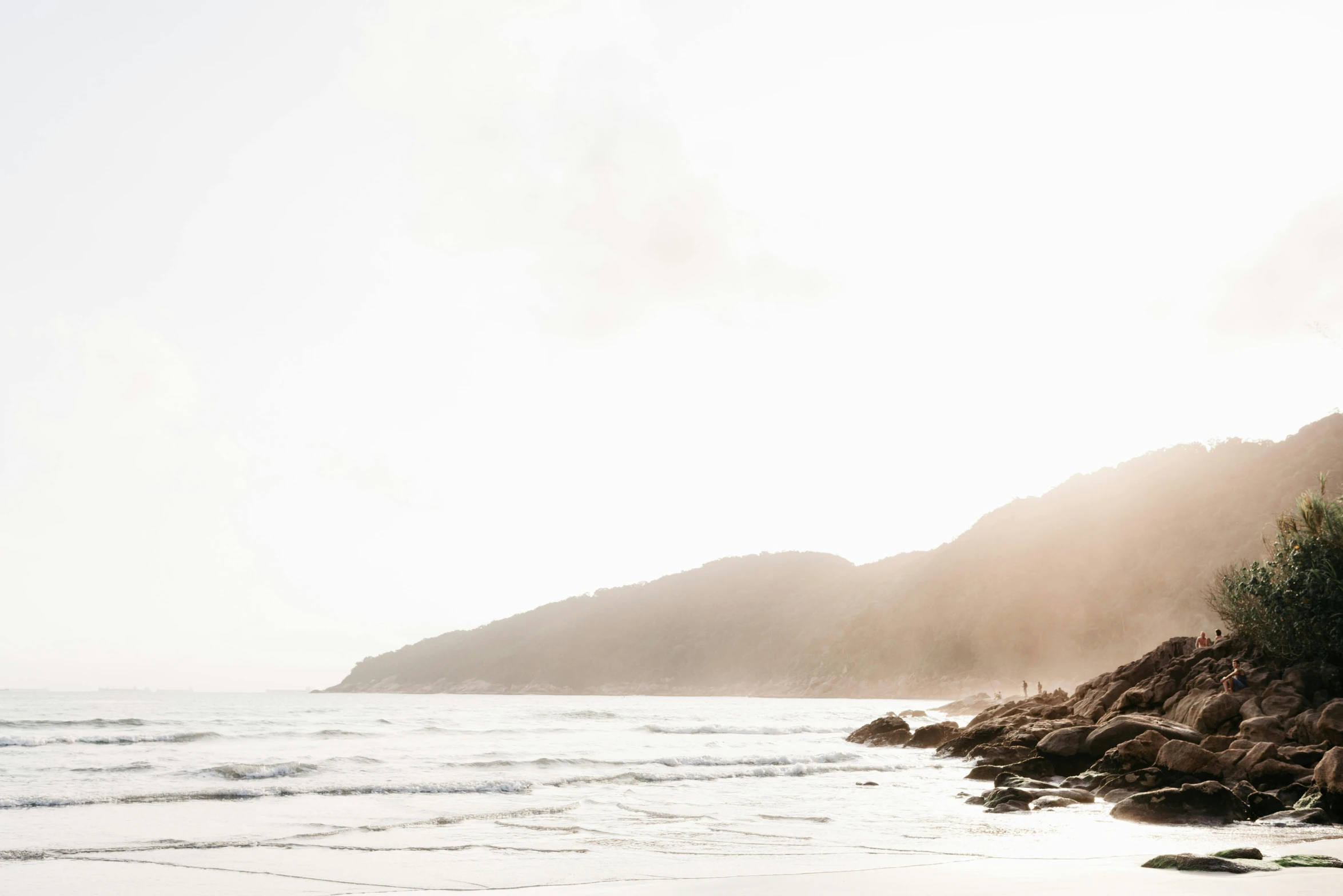 a man riding a surfboard on top of a sandy beach, unsplash contest winner, minimalism, rocky cliff, morning haze, abel tasman, light coming in from the left