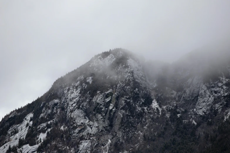 a mountain covered in snow on a cloudy day, pexels contest winner, figuration libre, light grey mist, ominous! landscape of north bend, high cliff, slightly pixelated