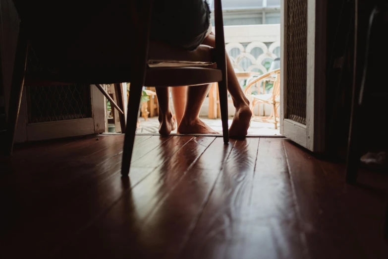a person sitting on a chair in front of a door, pexels contest winner, hardwood floors, legs intertwined, afternoon hangout, in the evening