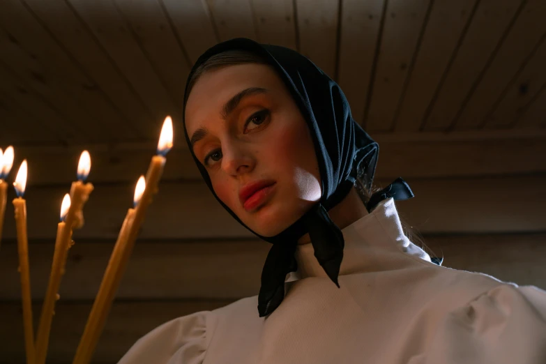 a woman standing in front of a bunch of candles, an album cover, inspired by Vasily Perov, pexels contest winner, renaissance, wearing a head scarf, nun fashion model, portrait sophie mudd, close-up portrait film still