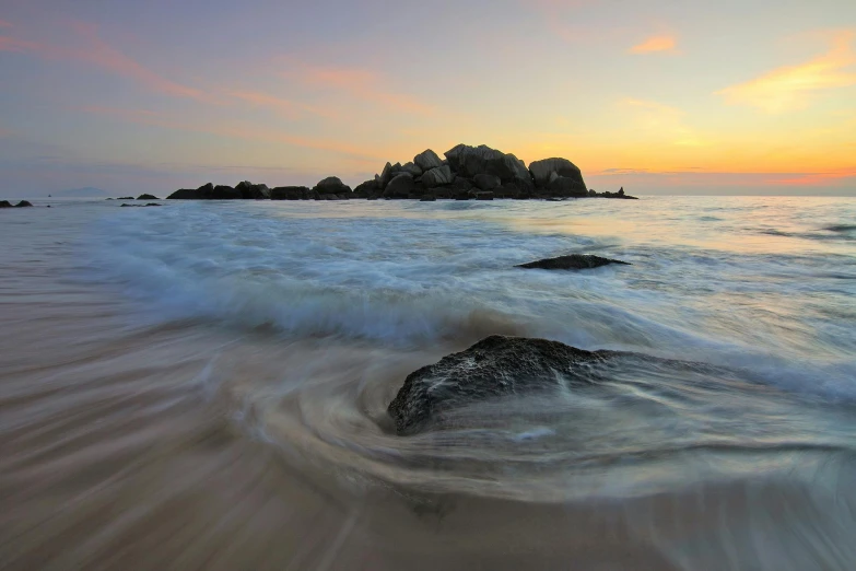 a large body of water sitting on top of a sandy beach, by Peter Churcher, unsplash contest winner, waves crashing at rocks, sunset beach, abel tasman, swirly ripples