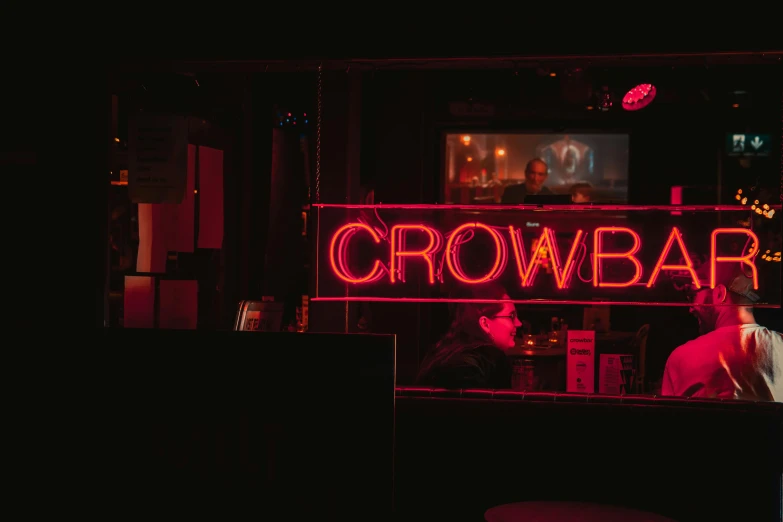 a man sitting at a bar in front of a neon sign, unsplash contest winner, lowbrow, crow, below is the crowd, crossbow, small red lights