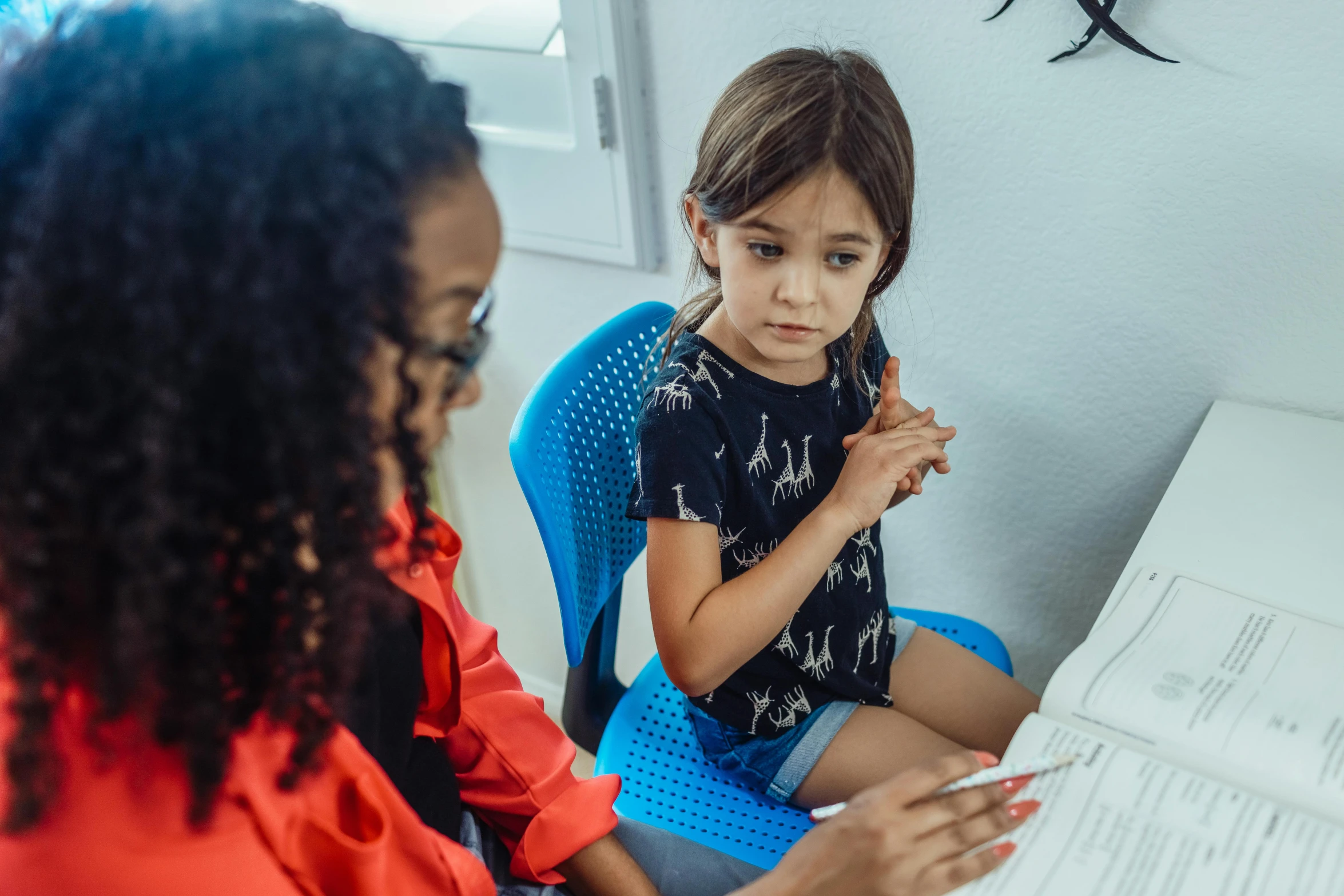 a woman and a little girl sitting at a desk, by Arabella Rankin, pexels contest winner, trying to read, isabela moner, healthcare, kid named finger