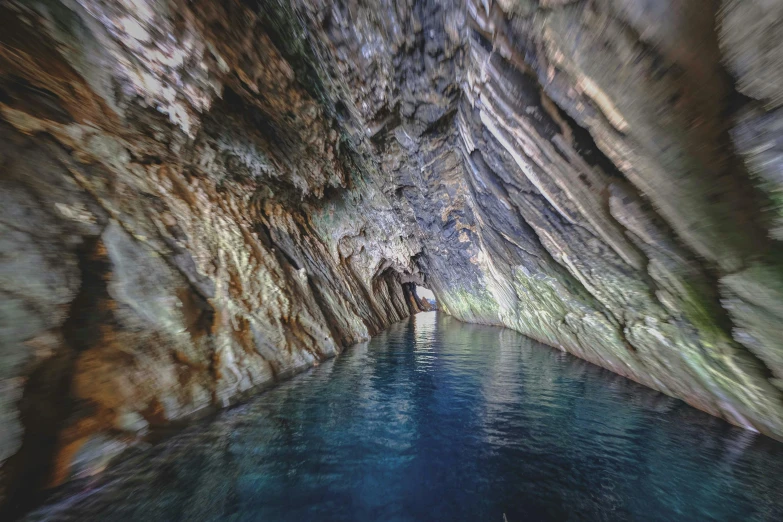 a man standing inside of a cave next to a body of water, lago di sorapis, head straight down, flume, thumbnail