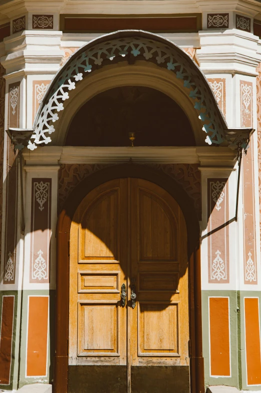 a large wooden door sitting on the side of a building, by Julia Pishtar, unsplash, arts and crafts movement, kremlin, sun lit, mosque interior, arched back