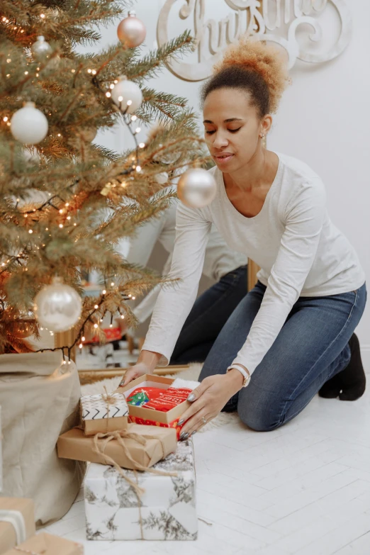 a woman opening presents in front of a christmas tree, bending down slightly, ashteroth, profile image, grey