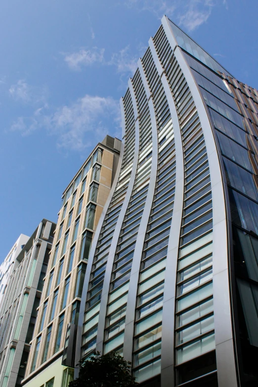 a very tall building with a lot of windows, inspired by Zaha Hadid, flickr, long street, curved body, shot from roofline, buttresses