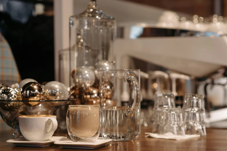 a wooden table topped with cups of coffee, inspired by Richmond Barthé, glass orbs, silver，ivory, cafe interior, brown