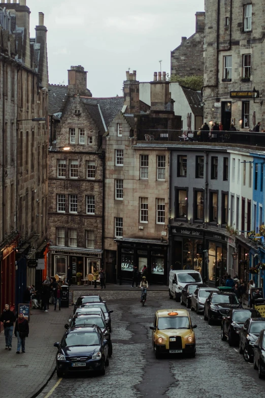 a street filled with lots of traffic next to tall buildings, by David Donaldson, pexels contest winner, renaissance, scottish style, staggered terraces, a quaint, a cozy