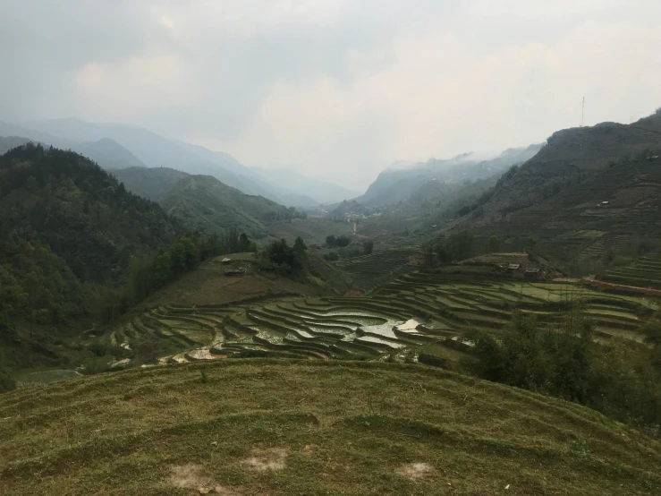 a group of people standing on top of a lush green hillside, by Daniel Lieske, happening, staggered terraces, bao pham, hills, seen from a distance