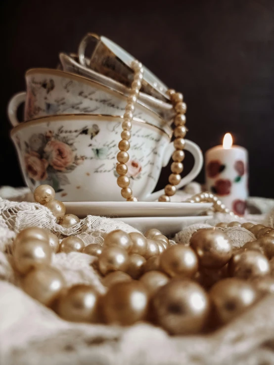 a bunch of pearls sitting on top of a table, a still life, inspired by Perle Fine, trending on unsplash, arts and crafts movement, tea cup, nostalgic and melancholic 4 k, low quality photo, antique photo