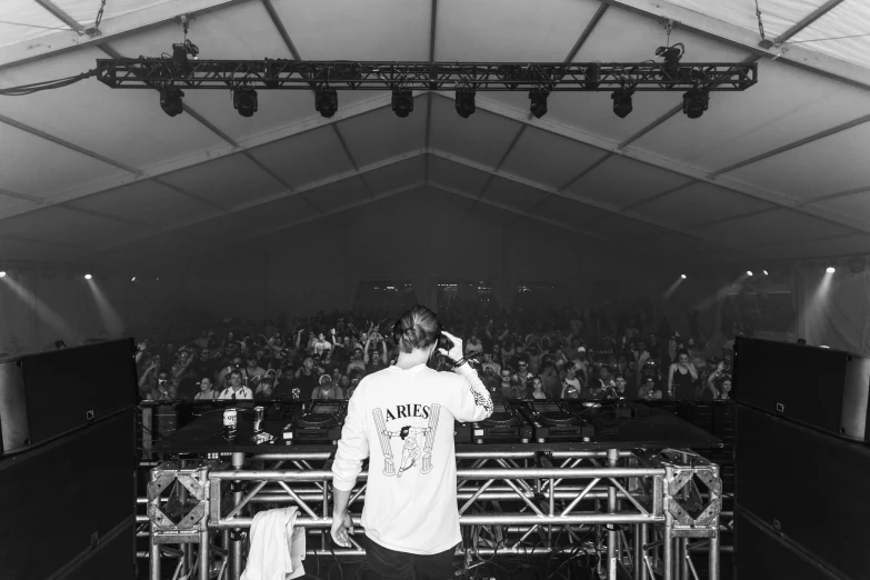 a man standing on a stage in front of a crowd, a black and white photo, by Austin English, dj, canopies, instagram post, marquee