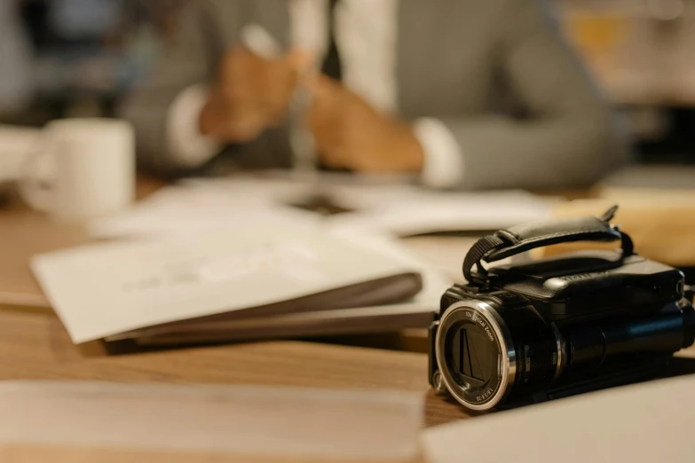 a camera sitting on top of a wooden table, a picture, film still from the office, background image, court session images, thumbnail